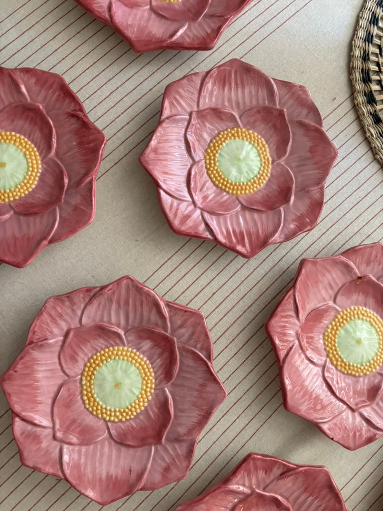 Pink flower-shaped plates with yellow centers on a textured surface

