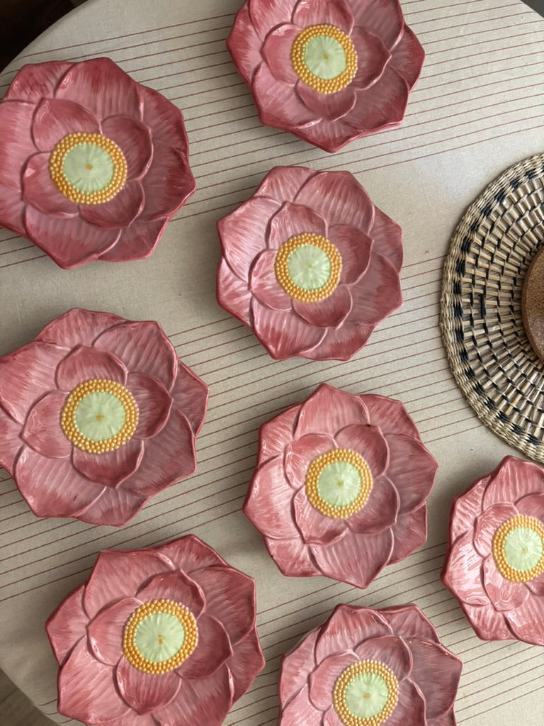 Pink flower-shaped plates with yellow centers on a textured surface.

